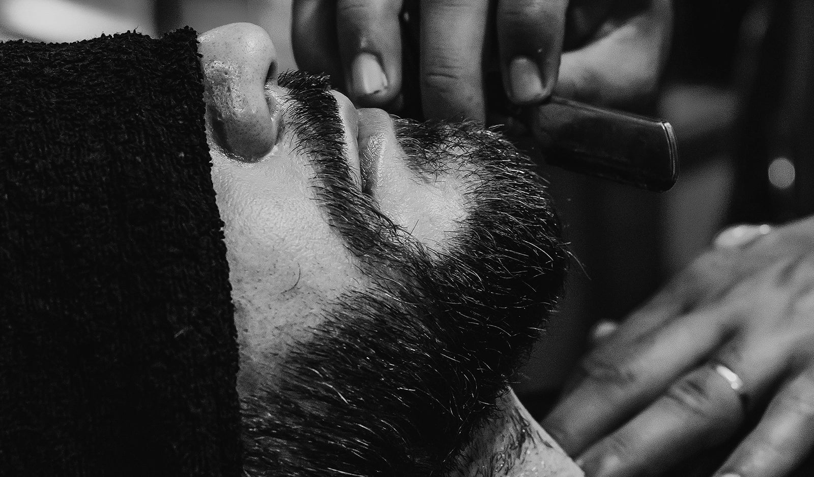 Barbershop-Szene: Konturenschneiden mit Rasiermesser während einer Nassrasur – professionelle Bartpflege in stilvollem Ambiente.