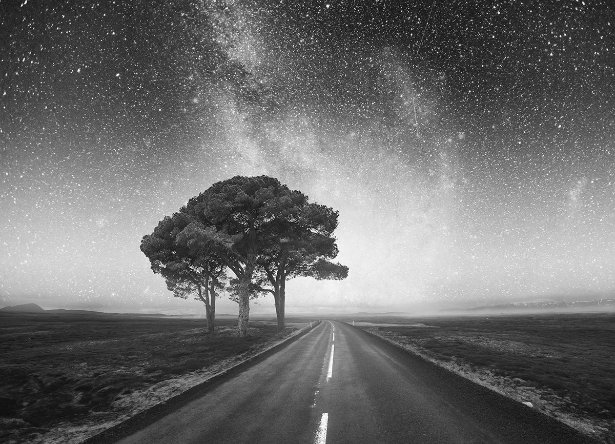 Einsame Straße, links ein einzelner Baum, unter einem klaren, leuchtenden Sternenhimmel – stimmungsvolle und mystische Nachtlandschaft.